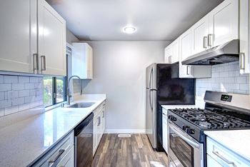 an empty kitchen with white cabinets and stainless steel appliances